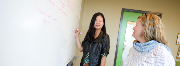 Two Blink employees collaborate on a whiteboard to create an Alexa skill